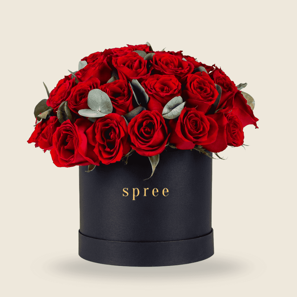 Round black hat box filled with red roses