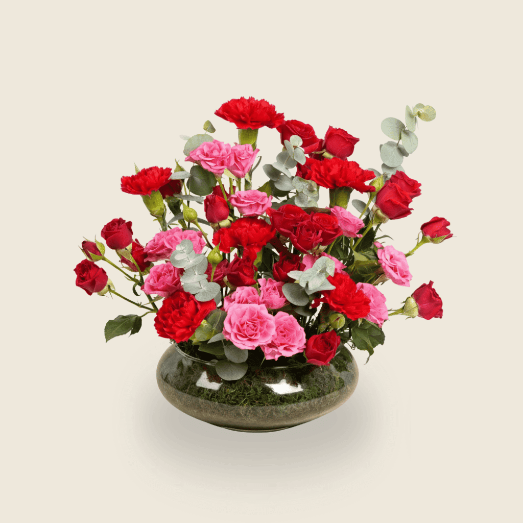Modern round arrangement of red and pink roses with eucalyptus leaves