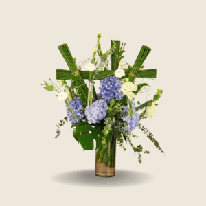 Tall glass vase with blue hydrangeas, white eustoma, and tropical greens