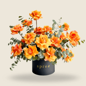 Vibrant orange roses in a black hatbox with eucalyptus