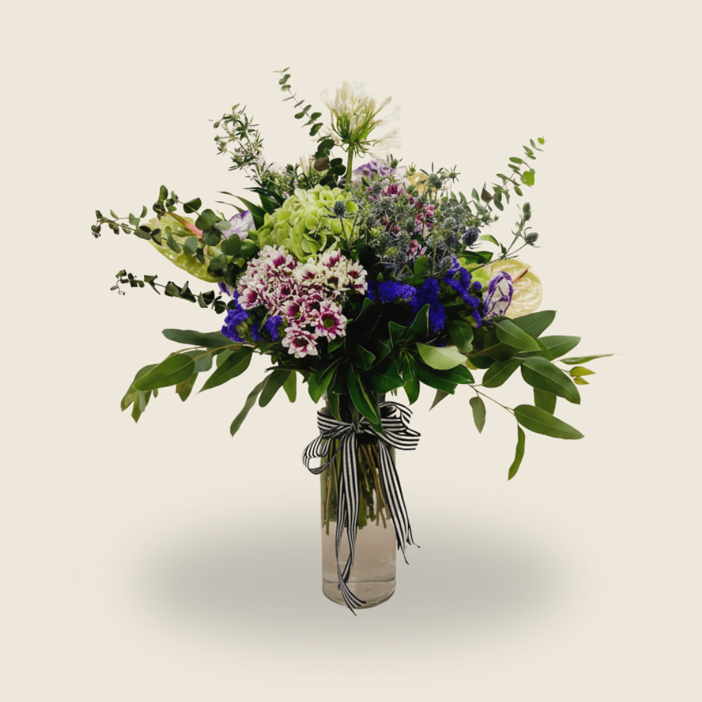 Tall green and purple vase arrangement with hydrangeas, anthuriums, and agapanthus